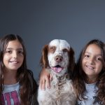 ο σκύλος ανάμεσα στα κορίτσια κι ένα χέρι στο λαιμό του σκύλου