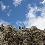 τρεις πεζοπόροι στη κορυφή ενός βράχου