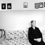 προσωπογραφία, ασπρόμαυρη φωτογραφία από γάμο. Η γιαγιά κάθεται στο καναπέ της κουζίνας και πίσω της ο τοίχος είναι γεμάτος πίνακες