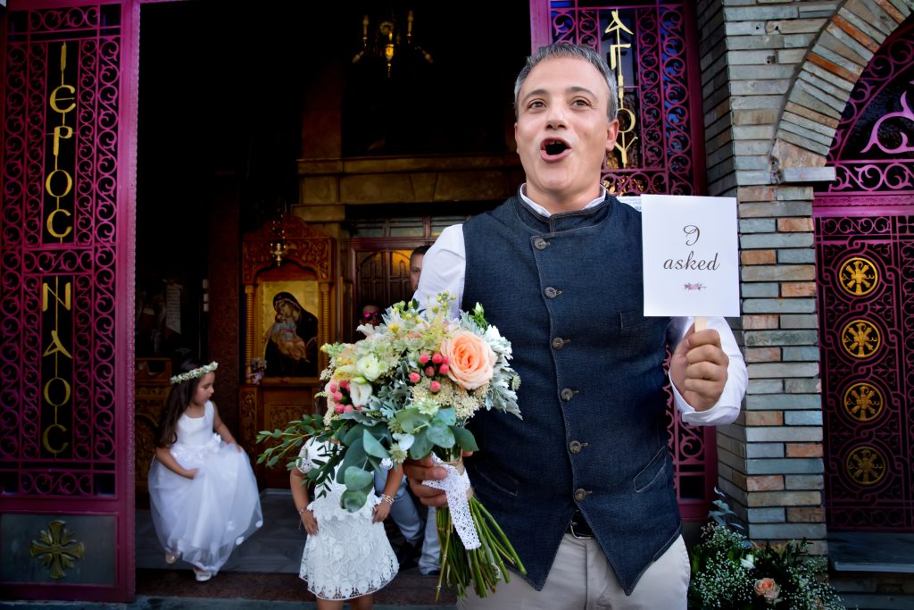 ο γαμπρός έξω από την εκκλησία. Κρατάει στο χέρι του μια ερώτηση.