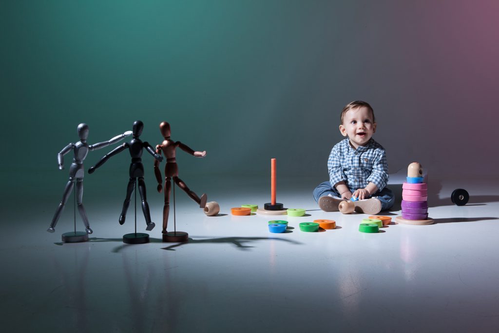 ο Δημήτρης χαμογελάει, δίπλα του βρίσκονται ξύλινα ανθρωπάκια