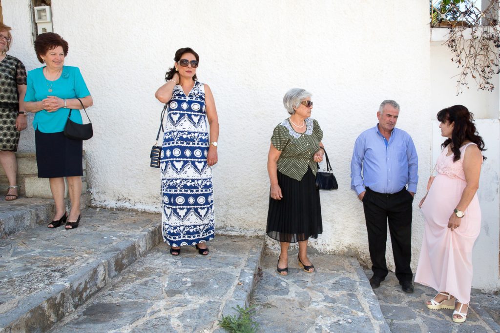 καλεσμένοι περιμένουν τη νύφη στα σκαλιά του πεζοδρομίου.