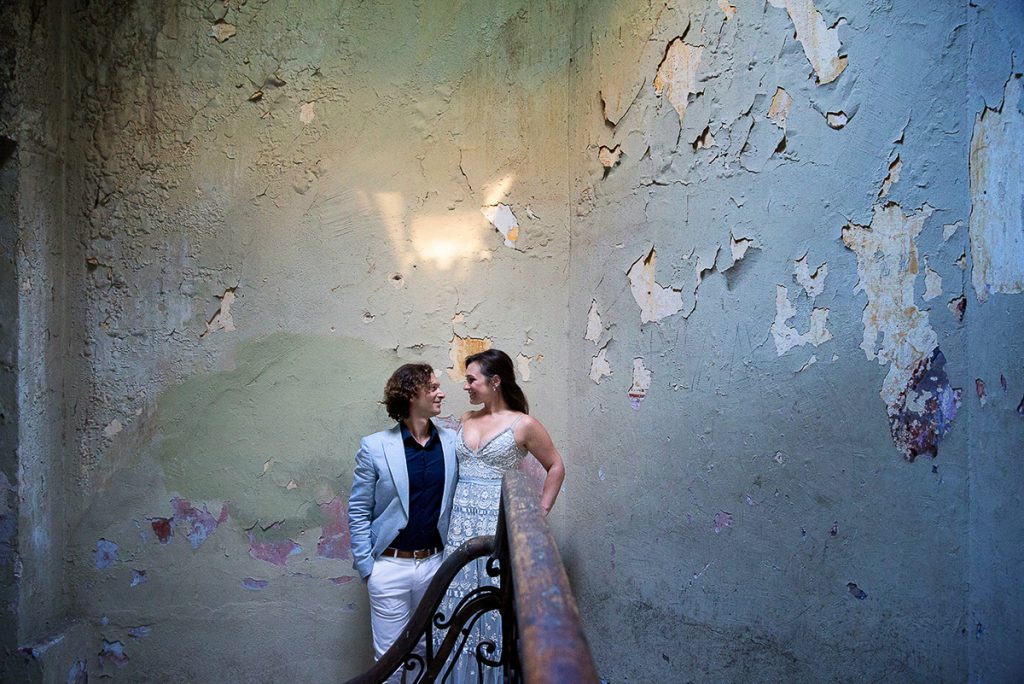 το ζευγάρι ακουμπάει σε ένα ξεφλουδισμένο τοίχο.