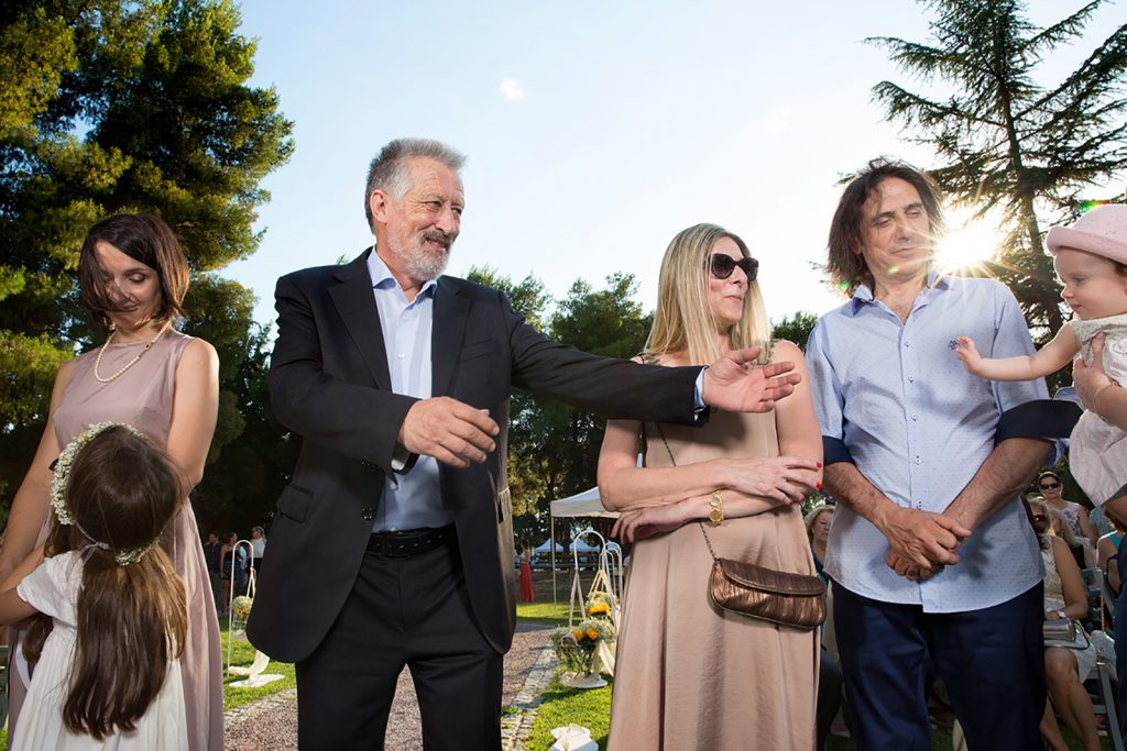 ο παππούς απλώνει τα χέρια να πιάσει τη μικρή, γάμος και βάπτιση μαζί, ο φωτογράφος γάμου παρουσιάζει μια γάμο βάπτιση στη Θεσσαλονίκη.