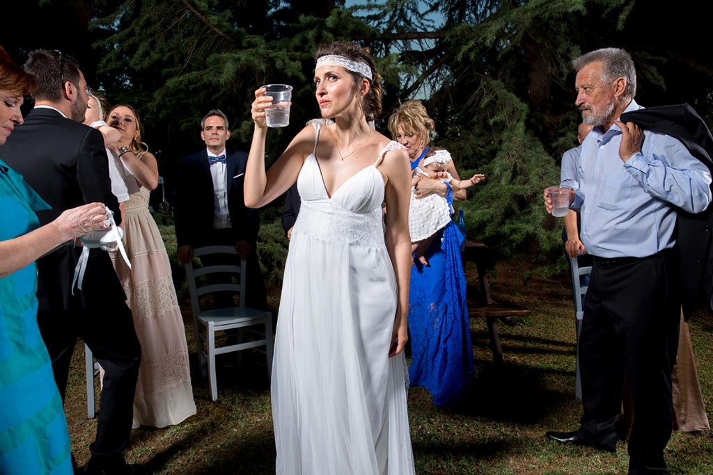η νύφη πίνει νερό, δίπλα της πολύς κόσμος