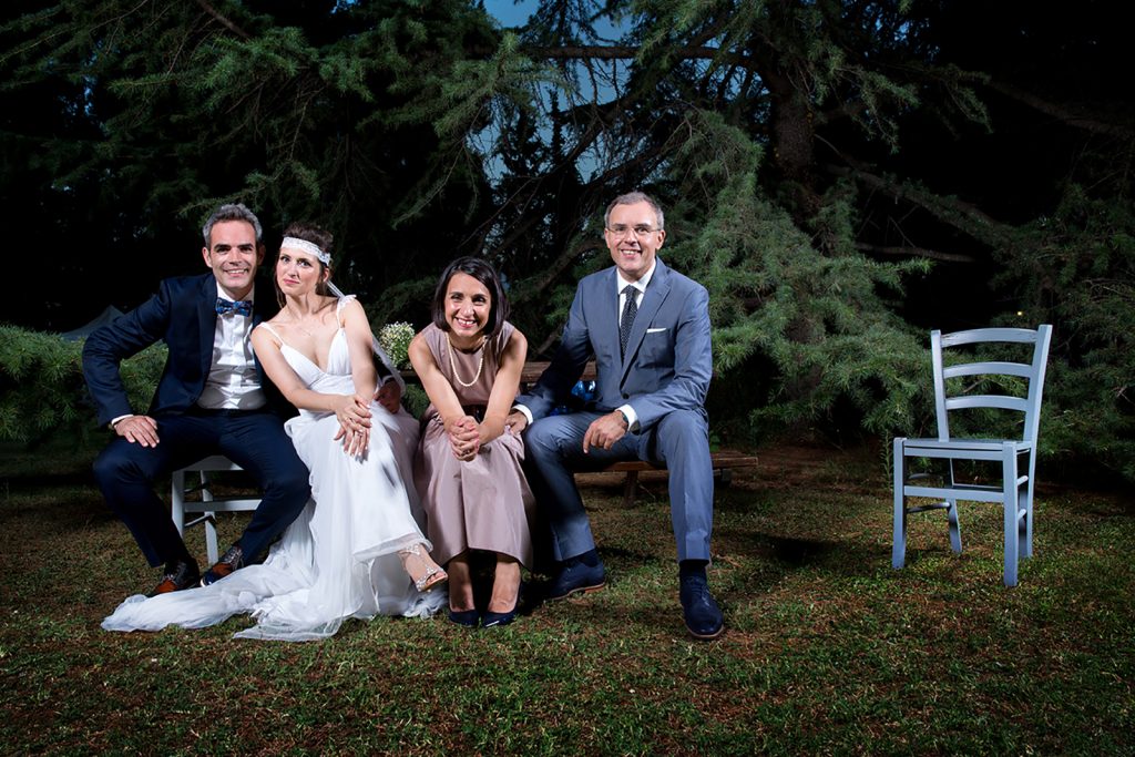 το ζευγάρι με τους κουμπάρους και μια ξύλινη καρέκλα δίπλα τους