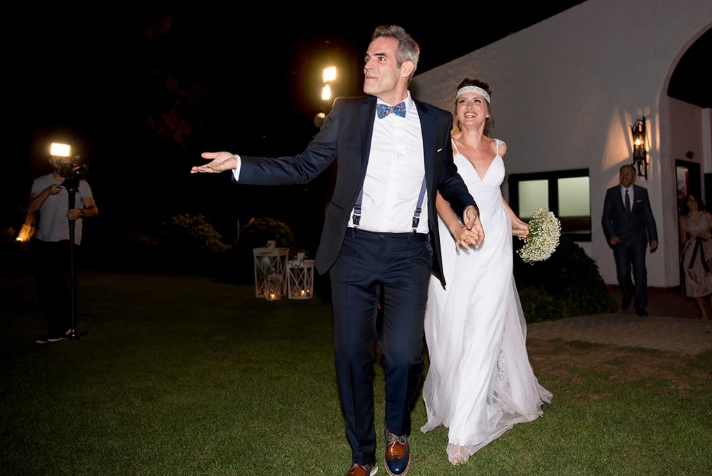 η είσοδος του ζευγαριού στη δεξίωση. Ο γαμπρός πρώτος μπαίνει στο χώρο , ακολουθεί η νύφη με χαμόγελο.