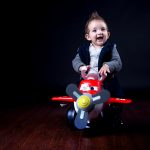 ο μικρός πάνω σε πλαστικό αεροπλανάκι χαμογελά στο φωτογραφικό φακό.