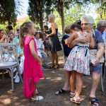 η γιαγιά αγκαλιάζει την εγγονή της, δίπλα ένα κοριτσάκι με φουξ φόρεμα τους κοιτάει.