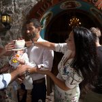 οι νονοί και οι γονείς προσπαθούν να βάλουν το καπέλο στο κεφάλι του μικρού.