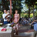 οι νονοί έχουν στην αγκαλιά τους το μικρό, δίπλα τους ένας πιστιρικάς πίνει νερό.