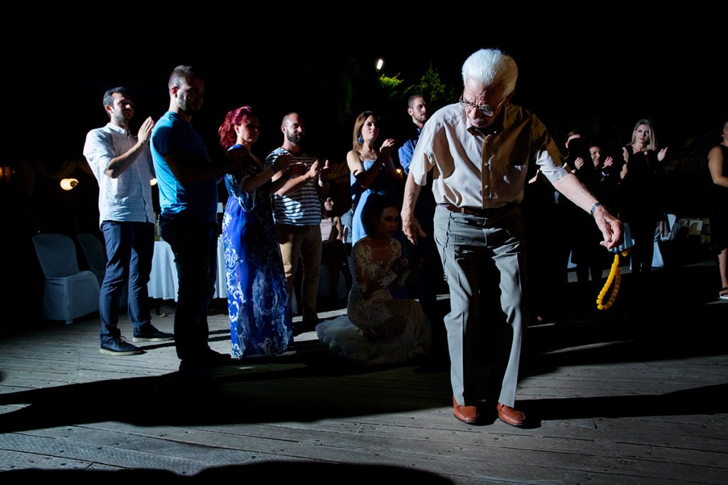 ένας παππούς χορεύει ζειμπέκικο με το κομπολοι του στα χέρια.